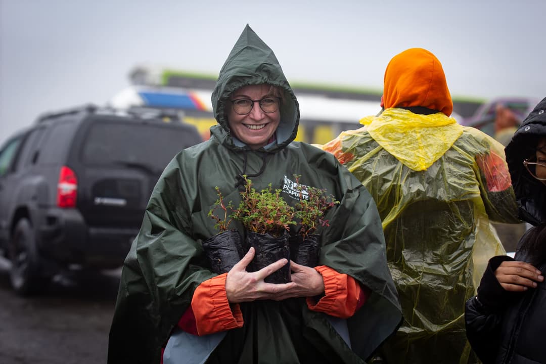Image of a smiling person holding a plant.