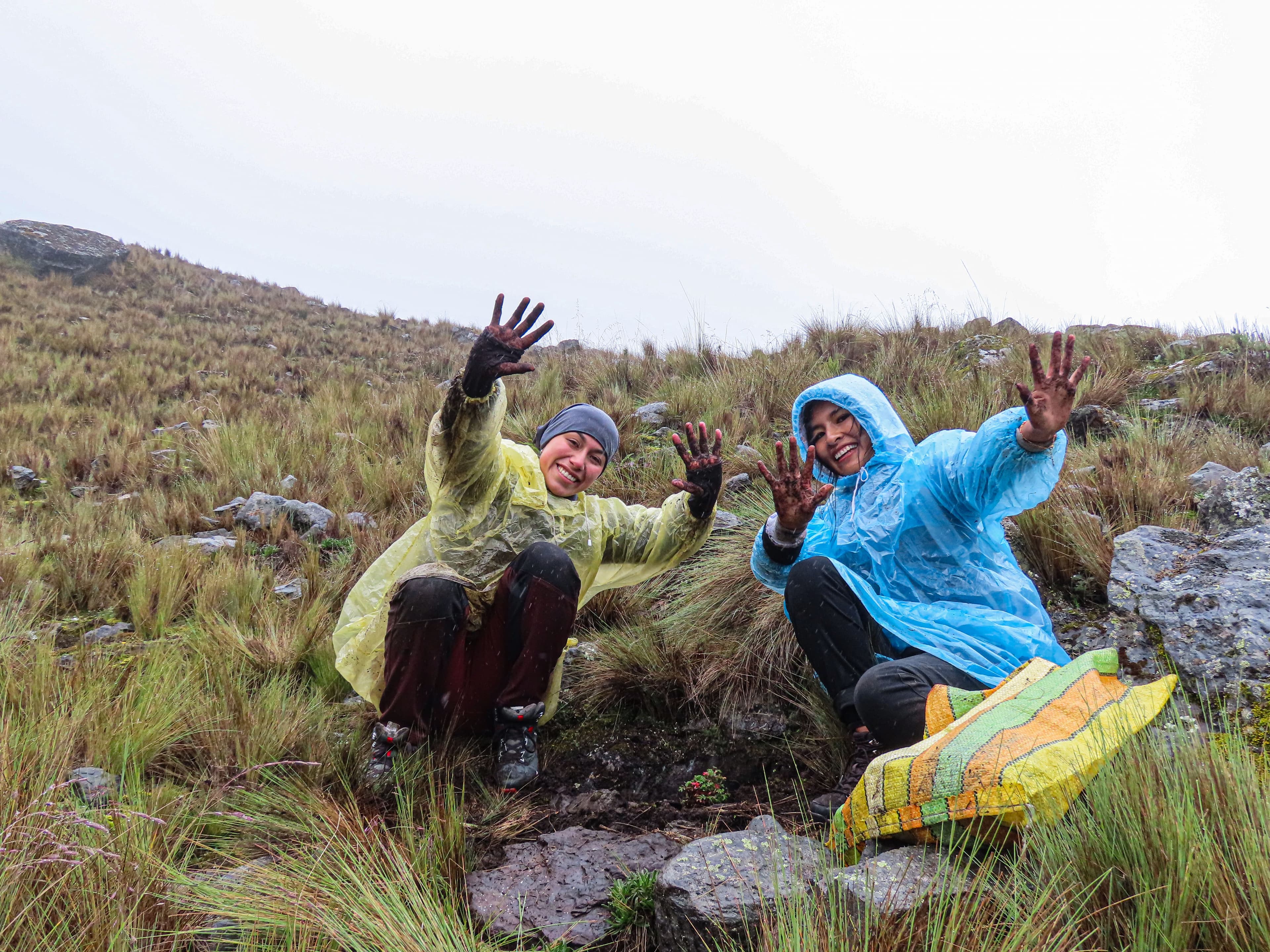 Two joyful people waving, with a mountain in the background