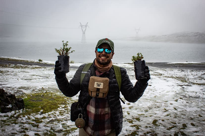 Image of a person smiling with two plants and fog in the background.